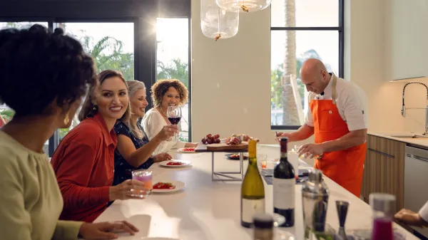 An image of a chef preparing food in a Flat while guest enjoying drinks at Evermore Orlando Resort.